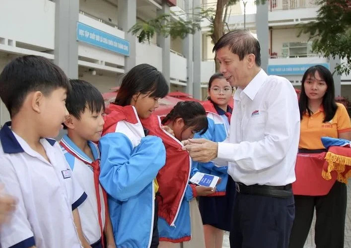 Nhà báo Nguyễn Khắc Văn, Quyền Tổng Biên tập Báo SGGP, trao áo ấm cùng học bổng đến các em học sinh tại xã Bình Lợi.